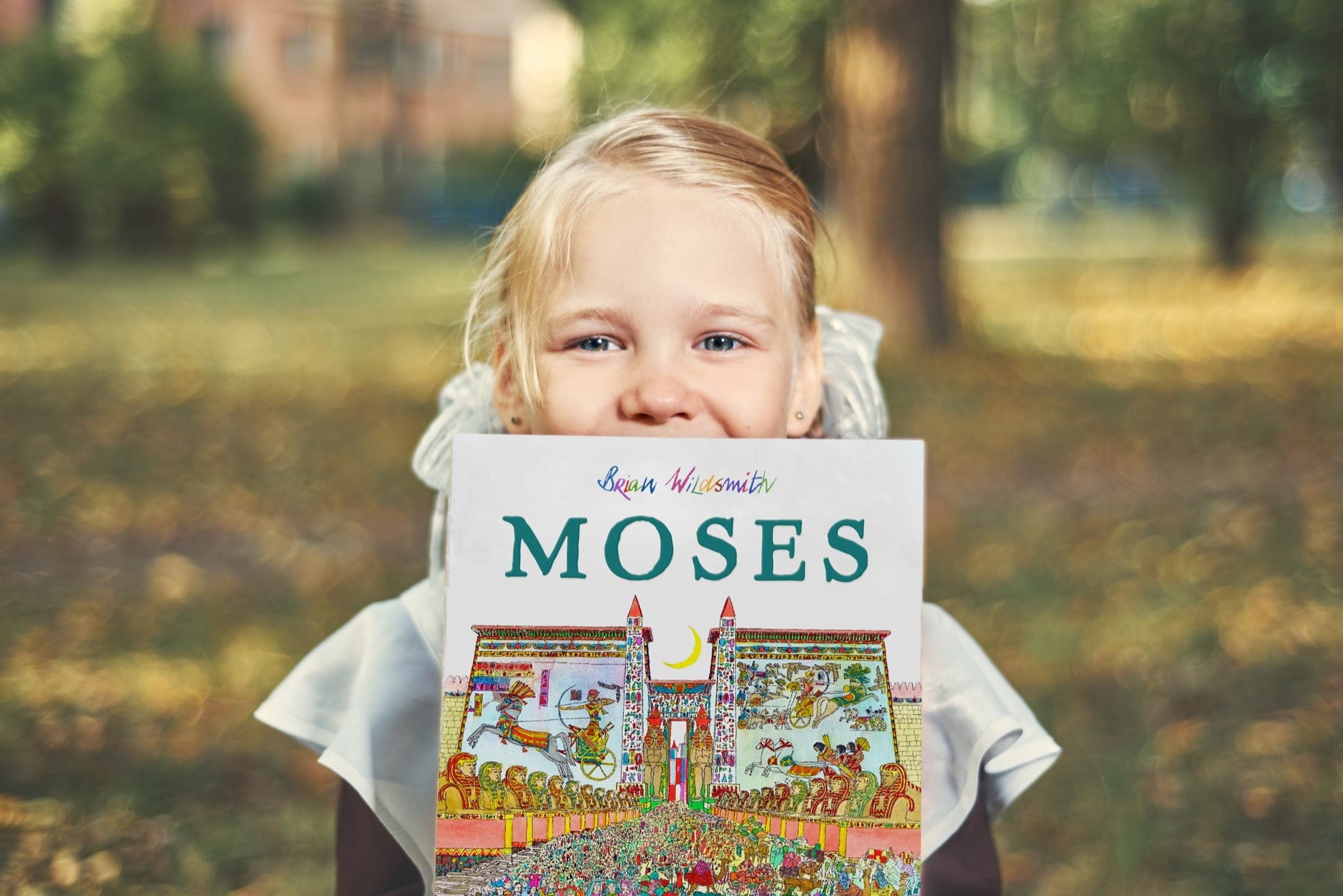 Young Reader with Moses Young reader holding Brian Wildsmith’s Moses